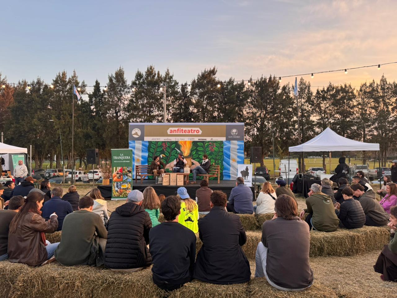 Anfiteatro al atardecer con gente sentada en fardos de paja